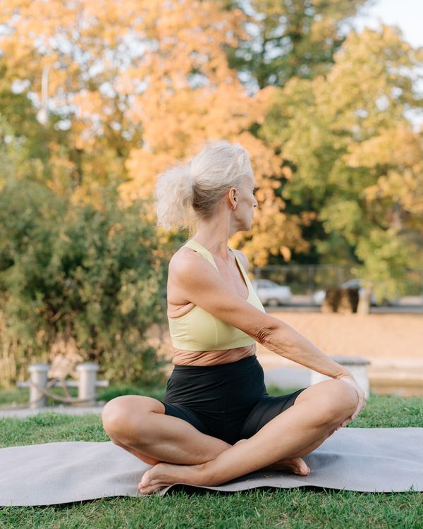 Person in a calm stretching pose outdoors, symbolizing balance and well-being.